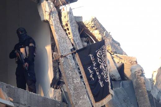 A fighter from an al-Qaida splinter group, the Al-Nusra Front, poses next to the movement's flag in the south of Damascus on September 22, 2014. Terrorist recruiters bringing fighters to Iraq and Syria have been traced to locations in Russia and Eastern Europe. (Rami al-Sayed/AFP/Getty Images)